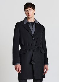 Cappotto lungo in misto lana nero con colletto a rever, vita con cintura e due tasche frontali. Presenta un colletto grigio e una silhouette strutturata.