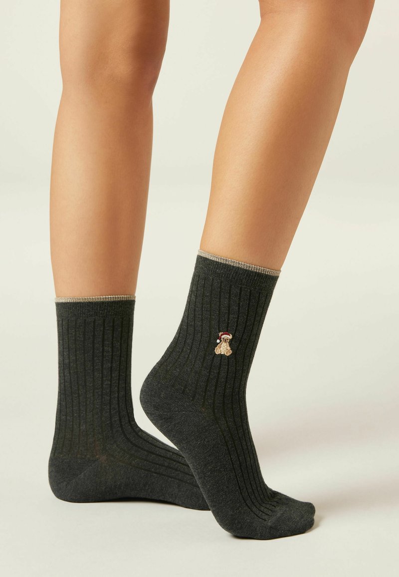 Mørkegrå ribbede ankelstrømper med en guldaccentueret manchet og broderet teddy-bear design nær anklen. Blød stoftekstur.