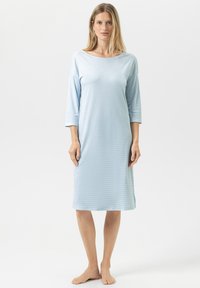 Jasnoniebieska, sięgająca do kolan koszula nocna wykonana z miękkiego materiału z delikatną prążkowaną fakturą i rękawami o długości 3/4. Brak widocznych zapięć.