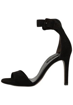 Schwarze Sandale aus Wildleder mit hohem Absatz, Knöchelriemen und Schnalle, offenem Zehenbereich und schlankem Stiletto-Absatz.