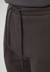 Pantaloni jogging grigi scuri caratterizzati da un tessuto morbido, cintura elastica e chiusura con cordino, con dettagli di marca alle estremità.