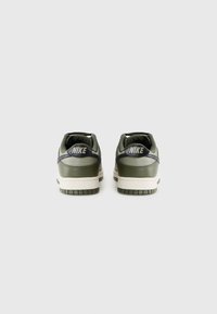 Olivengrønne Nike sneakers med glat læder, cremefarvet mellemsål og sorte accenter på hælen. Rund form, polstret krave og gummisul.