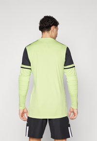 Langarm sportshirt in felgroen met zwarte accenten en schouderpadding; met een ronde halslijn en een aansluitend ontwerp.