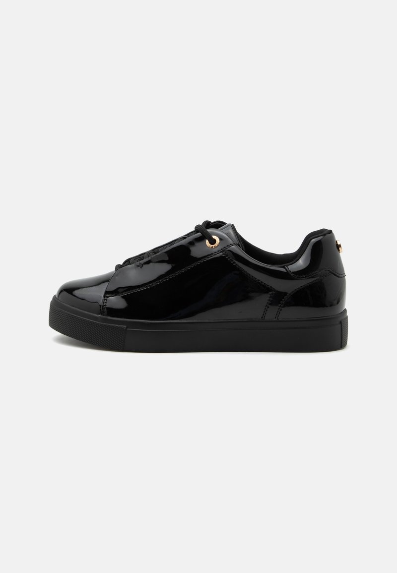 Baskets basses noires brillantes avec semelle noire, lacets noirs, œillets dorés et finition en cuir verni lisse, vues de profil.