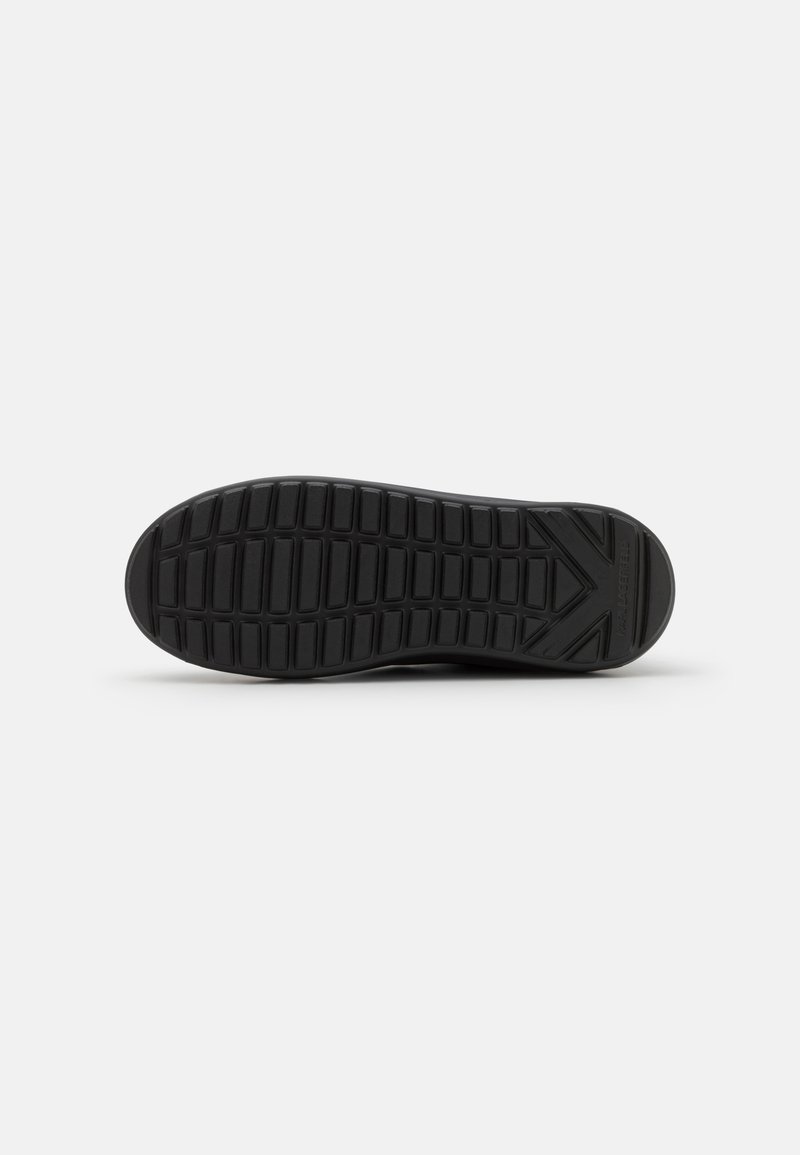 Schwarze Sneaker-Sohle mit einem strukturierten Muster aus horizontalen und vertikalen Rillen, mit einem Markenakzent an der Seite.