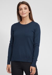 Mørkeblå genser, rund hals, lange ermer, ribbestrikkede mansjetter og kant, laget av mykt stoff med en glatt tekstur og subtil sømdetaljering.