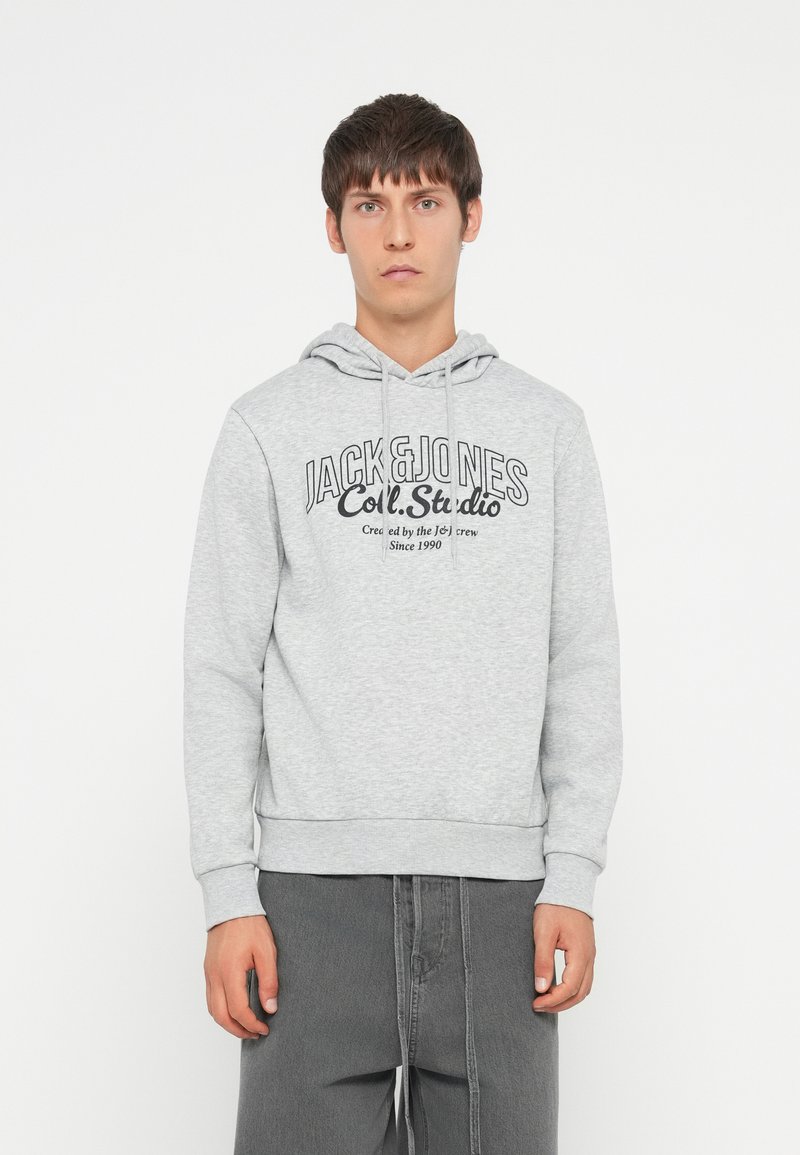 Sudadera gris con cordón, con un logo impreso "JACK & JONES Coll. Studio." Textura suave y puños y dobladillo acanalados.