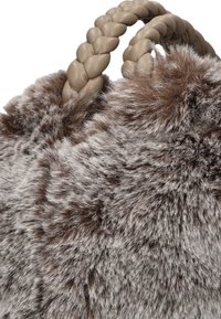 Borsa in pelliccia sintetica con una texture morbida grigia e marrone. Presenta manici intrecciati beige per un trasporto sicuro.