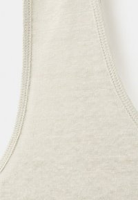 Gros plan sur un tissu tricoté beige clair avec une texture visible et des coutures courbes soigneusement réalisées le long des bords.