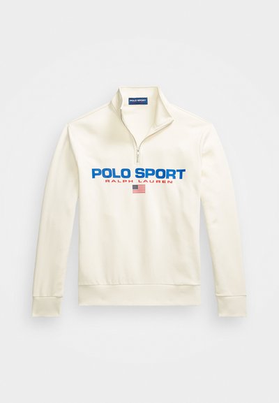 Pulover crem cu fermoar la jumătate, prezentând "POLO SPORT" în albastru și "RALPH LAUREN" în roșu, cu un accent al steagului american, realizat dintr-un material neted.