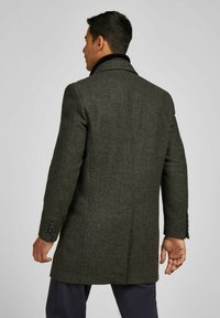 Donkergroene hertenhuid wollen jas met een notch-kraag, sluiting met één knoop en een getailleerde pasvorm. Leren accenten op de zakken en de mouwen.
