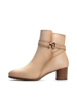 Bottine beige en cuir avec un petit talon en bois superposé et une bride décorative avec une boucle dorée sur le côté.