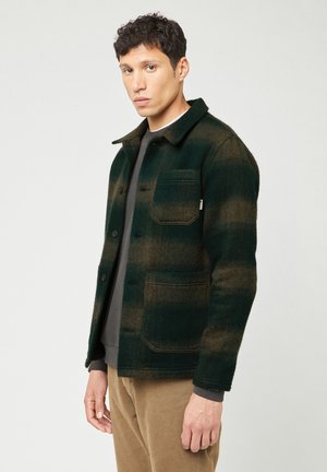 Shacket a cuadros verdes y marrones hecho de una mezcla de lana. Cuenta con un collar clásico, botones frontales y un bolsillo en el pecho.