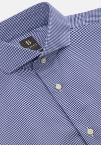 Blå och vit rutmönstrad skjorta med knappar och spridd krage. Har en diskret, texturerad tygkvalitet och etikett.