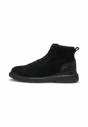 Baskets montantes noires avec semelle texturée, laçage à l'avant, col matelassé à la cheville et détail rouge subtil sur la languette du talon et de la languette.