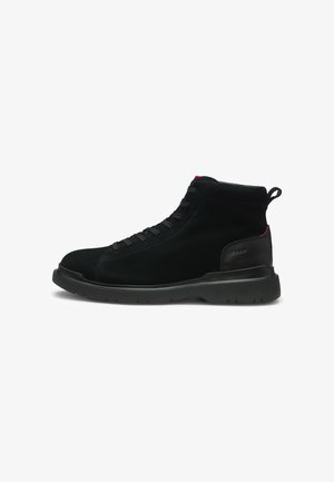 Czarny sneaker za kostkę z teksturowaną podeszwą, sznurowaniem z przodu, wyściełanym kołnierzem wokół kostki i subtelnym czerwonym detalem na pasku pięty oraz języku.