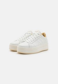 Des baskets en cuir blanc avec une semelle plateforme surélevée, un design texturé et un accent beige au niveau du talon. Elles disposent d'un système de fermeture à lacets et d'un détail de logo.