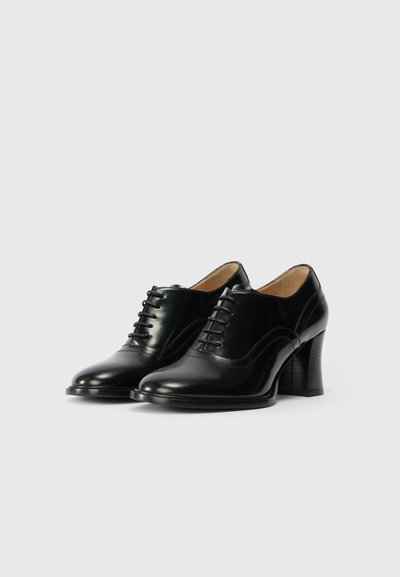 Black leather high-heeled shoes with a smooth finish, featuring a traditional lace-up design and subtle decorative stitching details.