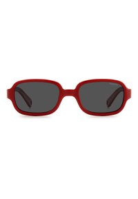 Lunettes de soleil en plastique rouge avec des verres ovales et teintés en gris foncé ; elles présentent des branches droites avec de légères courbes aux extrémités.