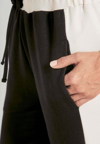 Zwart-witte joggingsbroek met een trekkoord in de taille, zachte, gestructureerde stof, zijzakdetails en een aansluitende pasvorm.