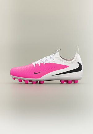 Crampon Nike blanc et rose avec logo swoosh noir, crampons moulés et lacets blancs, présenté en profil latéral sur un fond neutre.