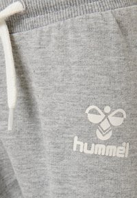 Grå joggingbyxor med en strukturerad tyg, elastisk midja med en vit snörning, och en vit logotyp på benet.