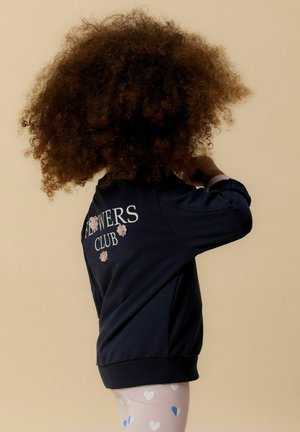 Navy sweatshirt with "FLOWERS CLUB" text and floral embroidery on the back, paired with light pink leggings featuring heart patterns.