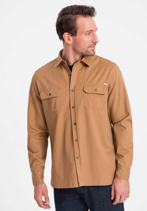 Lichtbruine, langmouw shirt met knoopsluiting en twee borstzakken. Gemaakt van soepele stof, met een subtiele logo-accent op de zak.