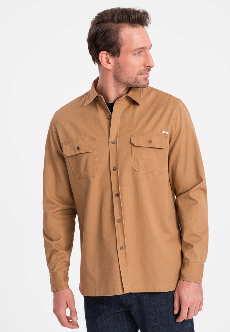 Lichtbruine, langmouw shirt met knoopsluiting en twee borstzakken. Gemaakt van soepele stof, met een subtiele logo-accent op de zak.