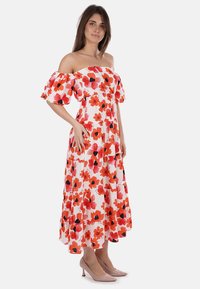 Abito maxi off-the-shoulder bianco con motivo floreale rosso e nero, maniche corte a sbuffo, vita arriccinata e gonna fluida.
