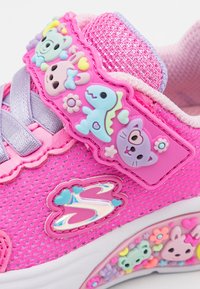 Różowe siatkowe sneakersy z kolorowymi gumowymi ozdobami, rzepem oraz błyszczącym logo po boku, z wzorzystą podeszwą.