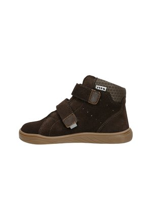 Bottine en suede marron, avec deux bandes Velcro, semelle en caoutchouc beige, panneau arrière texturé et accents cousus.