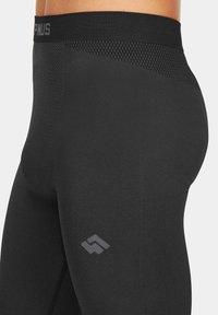 Czarne legginsy sportowe z teksturowanym wysokim pasem, z kontrastowym logo w odcieniu szarości oraz eleganckim, elastycznym materiałem.