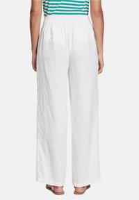 White linen wide-leg pants with an elastic waistband, featuring two back pockets and a textured finish. Sandals visible at the bottom.