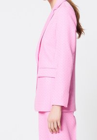 Blazer rosa su misura con vestibilità slim, caratterizzato da un sottile motivo testurizzato, rever a intaglio e una tasca sul petto.
