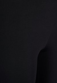 Black leggings made from a soft, stretchy fabric, featuring a smooth texture and a snug fit, without visible seams or patterns.