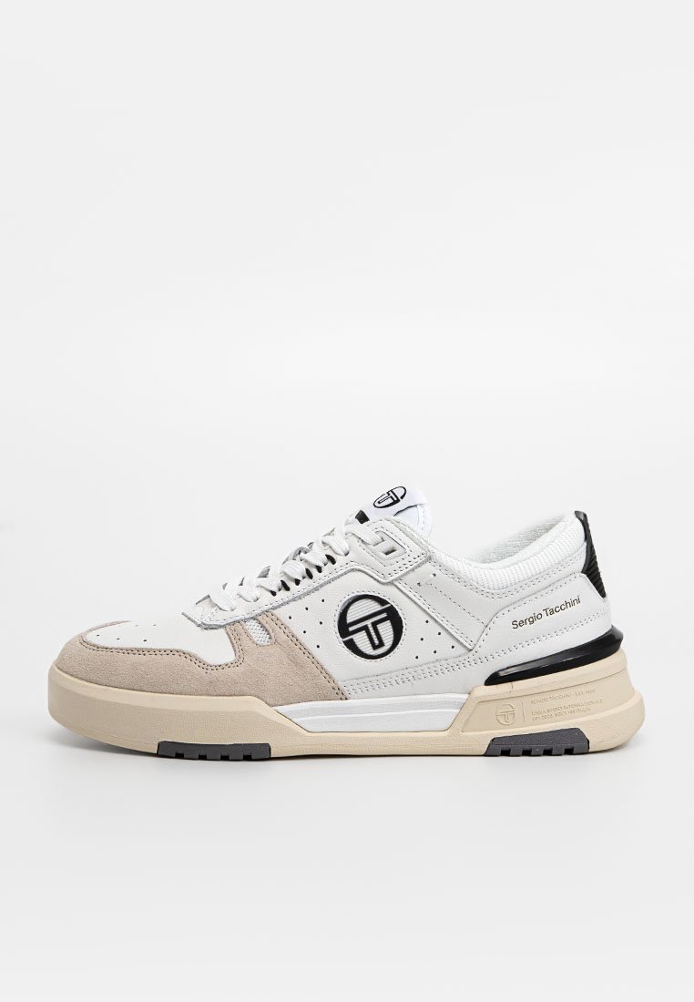 Sneaker bianca e beige chiaro con tomaia in suede e pelle testurizzata, con dettagli neri, logo e una suola in gomma spessa.