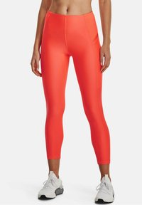 Höga, figurnära leggings i starkt orange, tillverkade av ett stretchigt material; har en slät yta och minimala sömmar.