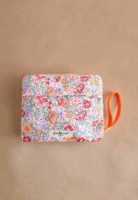 Quiltad påse i pastellrosa med blommönster och snäckmönster. Har ett orange tyghandtag och en vit logotypetikett i botten.