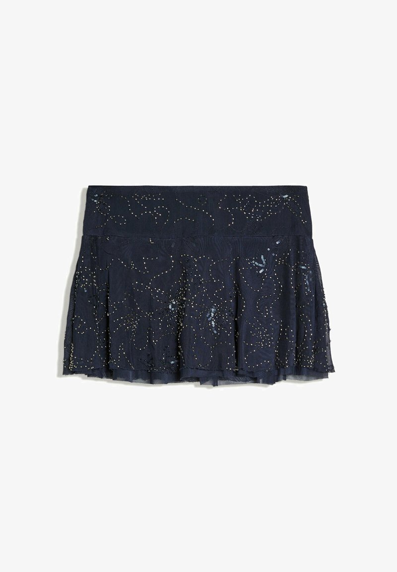 Jupe plissée bleu marine foncé avec des embellissements en sequins et perles créant un motif subtil en spirale sur une superposition de tissu transparent.