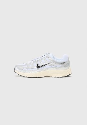 Biało-srebrne buty sportowe Nike P-6000 z czarnym logo swoosh i beżową podeszwą, pokazane z zewnętrznej strony na jednolitym jasnym tle.