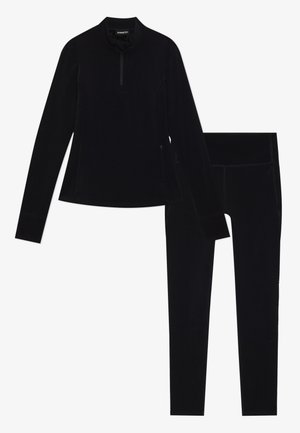 Musta urheiluasu, joka koostuu pitkähihaisesta paidasta, jossa on puoliveto kaulus, sekä vastaavista leggings-haalareista. Ominaisuuksiin kuuluu sileä pinta, jossa on minimaalisesti saumoja.
