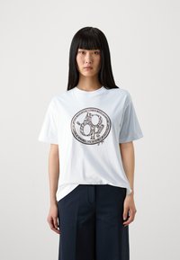 T-shirt en coton blanc avec un graphique circulaire noir comportant des motifs abstraits, à manches courtes et à coupe décontractée.