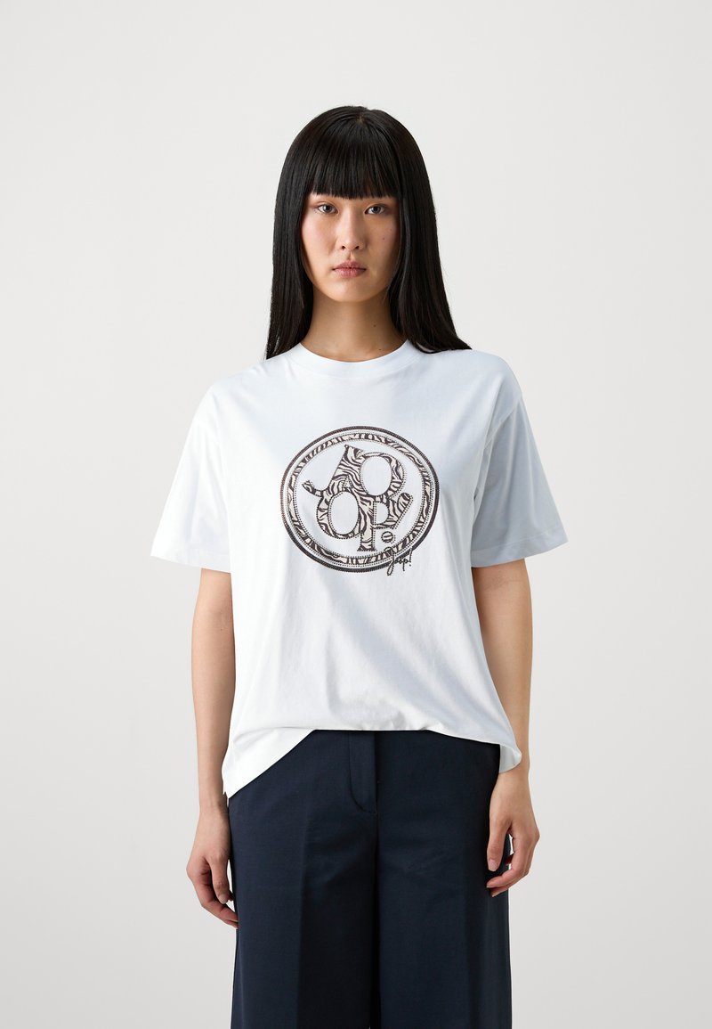 T-shirt en coton blanc avec un graphique circulaire noir comportant des motifs abstraits, à manches courtes et à coupe décontractée.