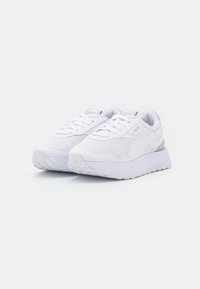 Chaussures de sport blanches avec une tige en mesh, une languette rembourrée et une semelle en caoutchouc texturée. Présentent un logo discret et des accents de design en couches.
