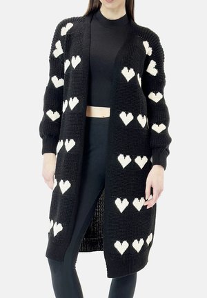 Cardigan nero in maglia con motivi a cuori bianchi, maniche lunghe, apertura frontale e polsini a coste. Tessuto leggero, design lungo fino al ginocchio.