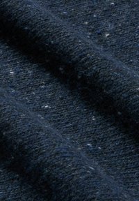Granatowo-niebieska tkanina tkana z teksturowaną powierzchnią, z jasnymi plamkami oraz miękkim, ciepłym wyglądem, złożona w łagodne fale.
