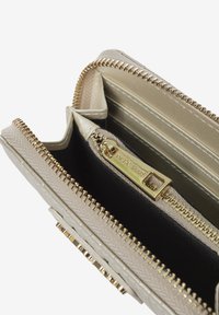 Portafoglio beige con una superficie testurizzata, hardware dorato e svariati scomparti. Presenta una chiusura a zip e un interno liscio e lucido.