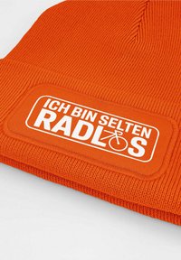 Orange knitted beanie featuring a rectangular white patch with the text "ICH BIN SELTEN RADLOS" and a bicycle icon. Text is centered.