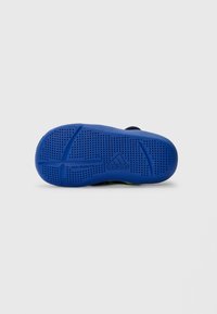 Blue rubber outsole with textured grip pattern and "adidas" branding; features non-marking design and curved shape for comfort.